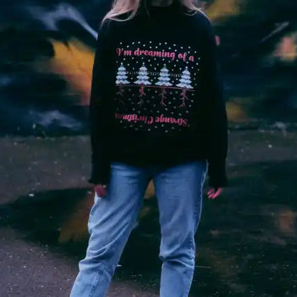 Person wearing a black sweater with text and graphics, standing against a colorful mural.