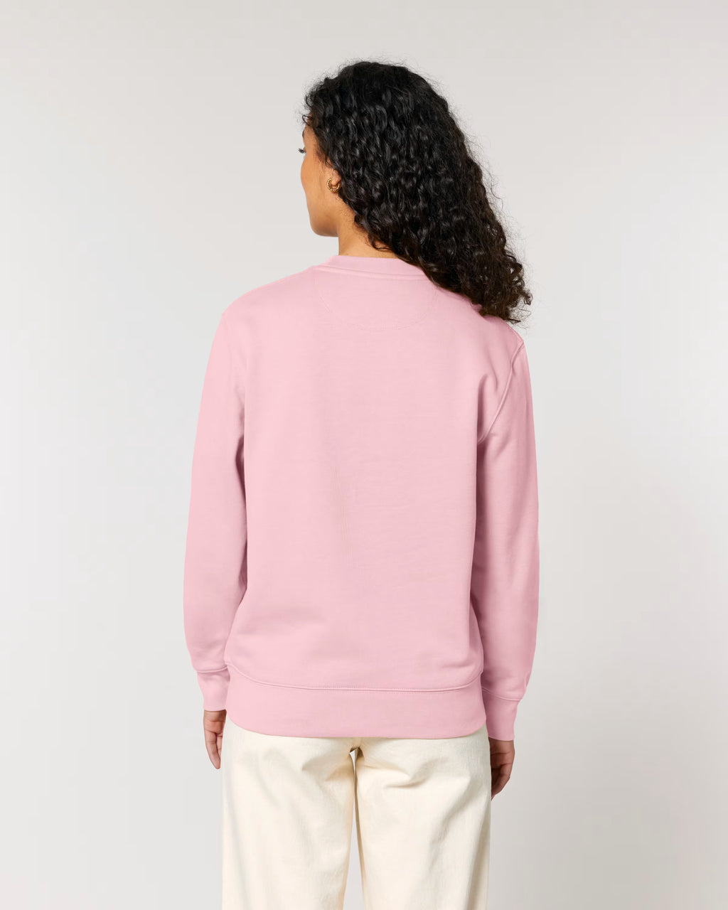 Person wearing a pink sweatshirt and white pants on a plain background