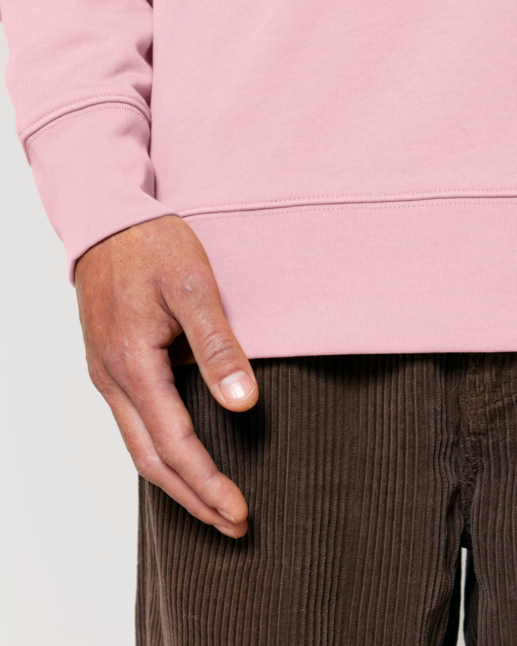 Close-up of a hand wearing a pink sweatshirt on a light gray background