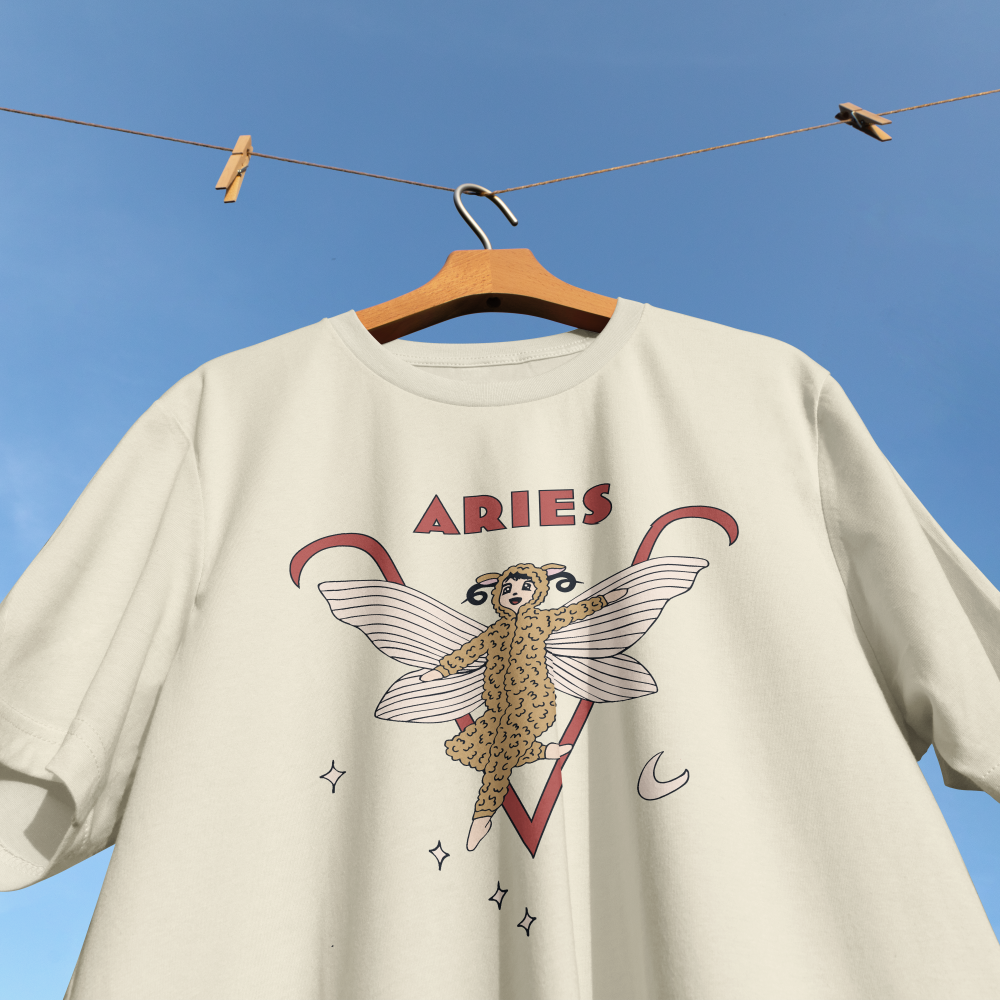Beige t-shirt with Aries zodiac design on a hanger against a blue sky.