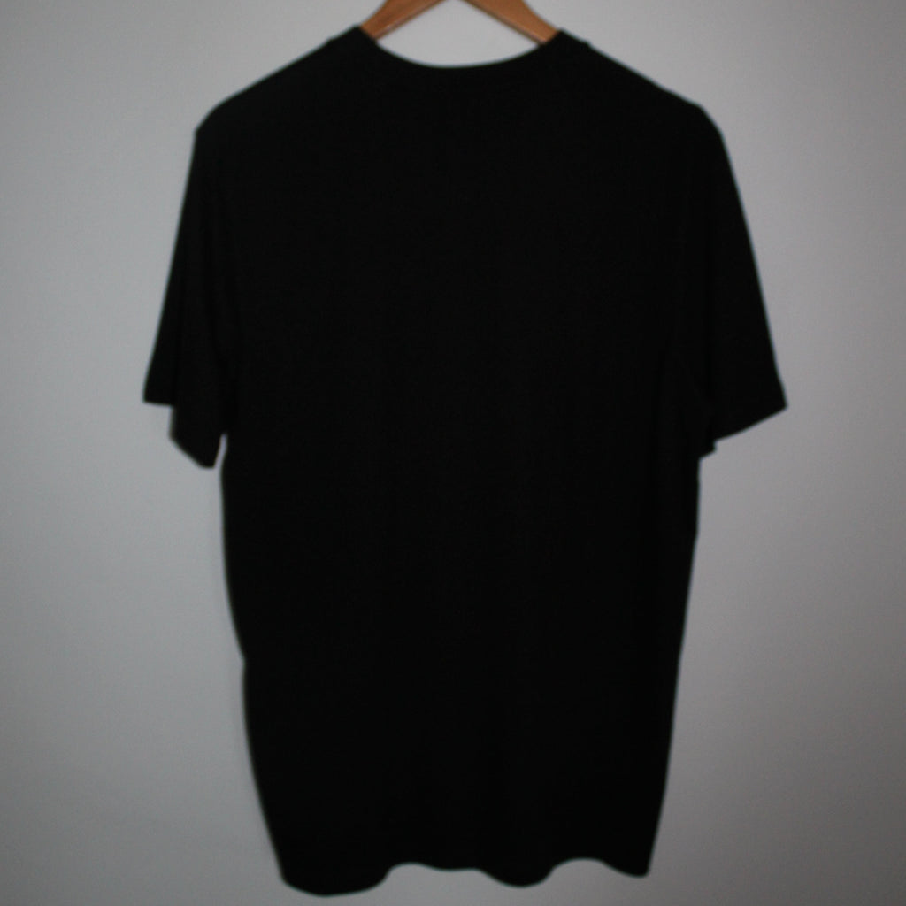 Black tee on a hanger against a plain background