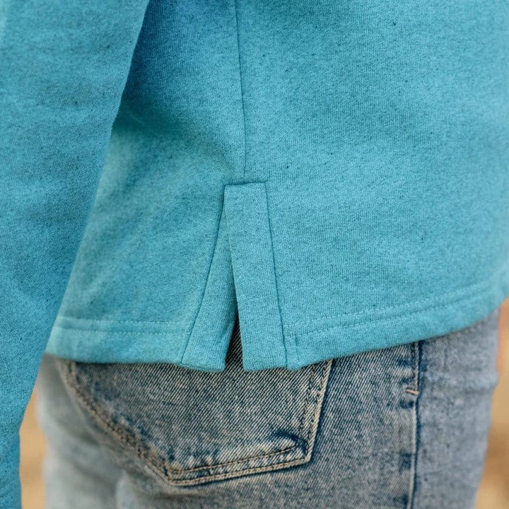 Close-up of a person wearing a blue shirt and jeans with a blurred background