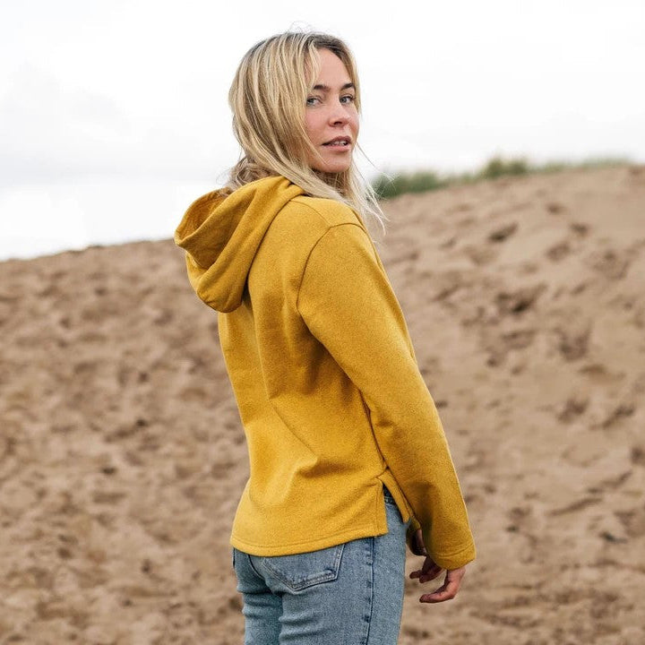 Person wearing a yellow hoodie standing in a desert-like landscape
