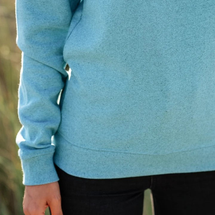 Person wearing a light blue sweatshirt with a blurred background