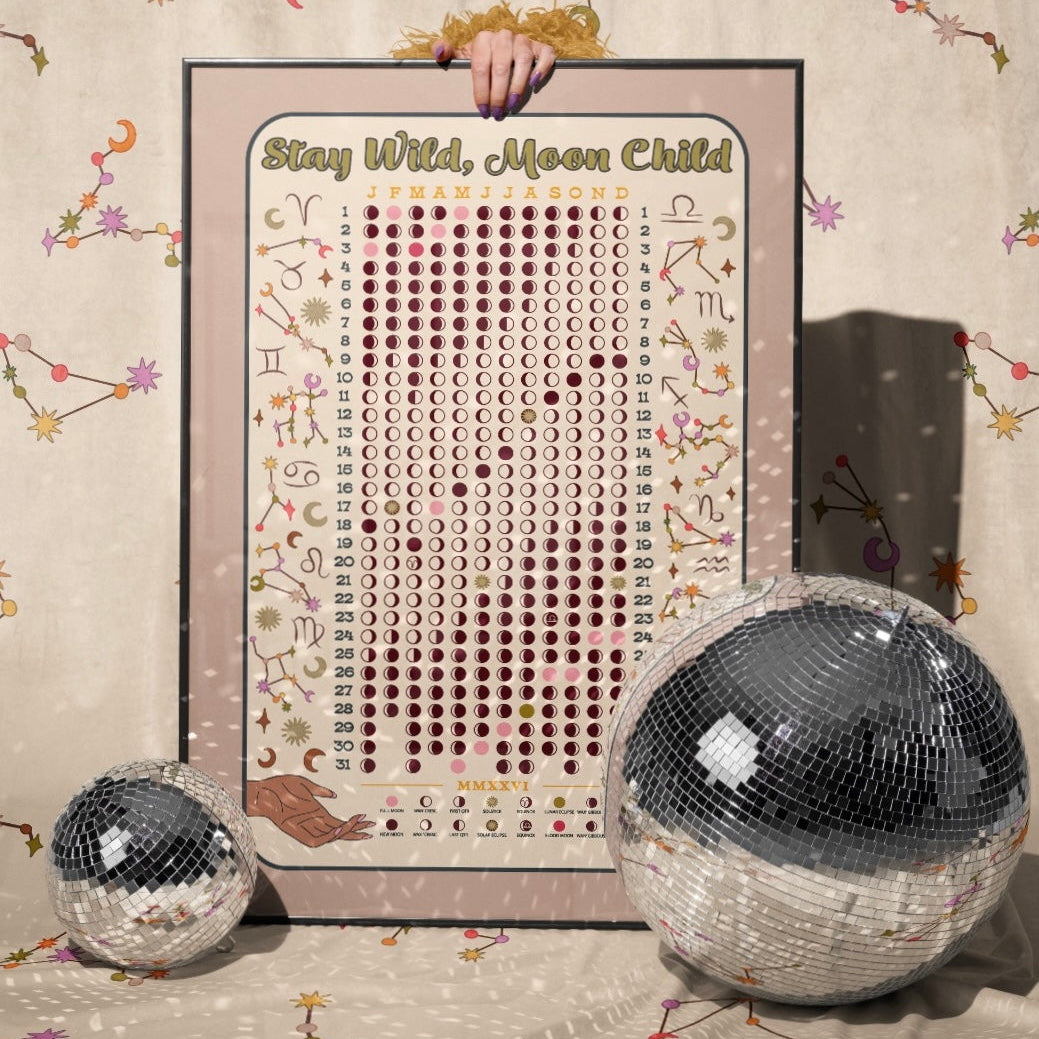 Decorative poster with 'Stay Wild, Moon Child' text, held by a hand, with disco balls and celestial decorations on a patterned background.