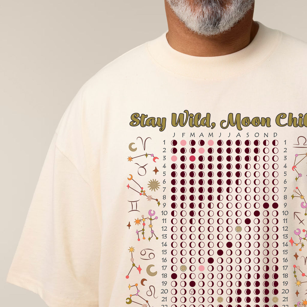 Person wearing a cream t-shirt with celestial design and text